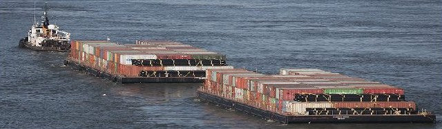 A tug pulling two barges stacked with sea containers