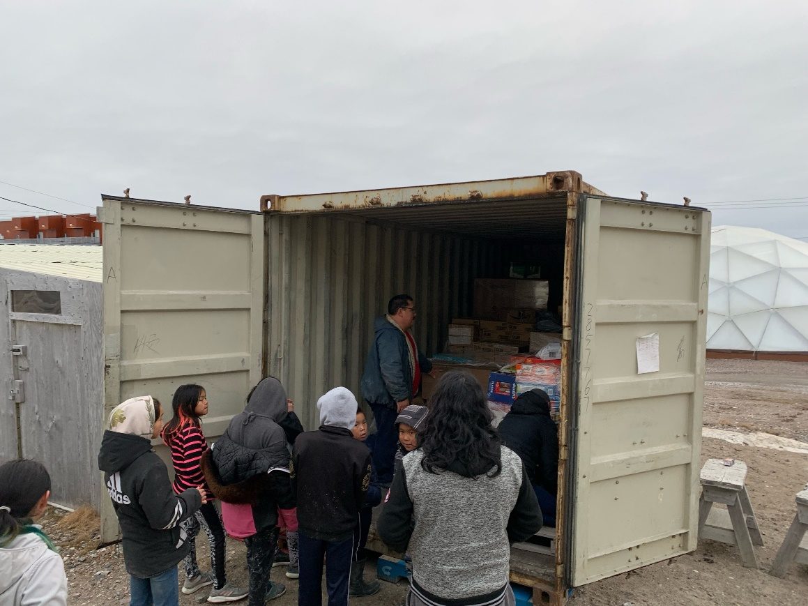 Community members gather at an open sea container on delivery day