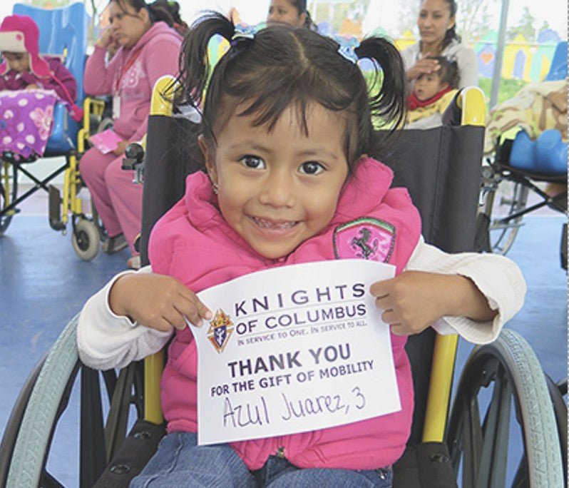 A smiling young girl holds a Knights of Columbus thank-you card